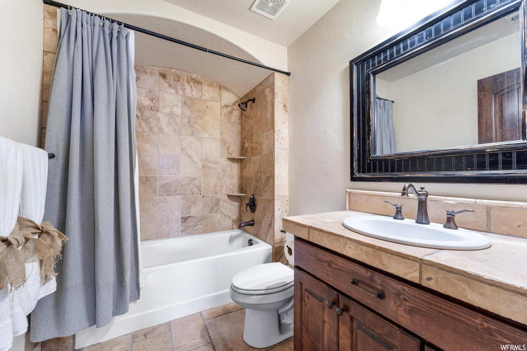 full bathroom with tile flooring, toilet, shower curtain, mirror, bathtub / shower combination, and vanity