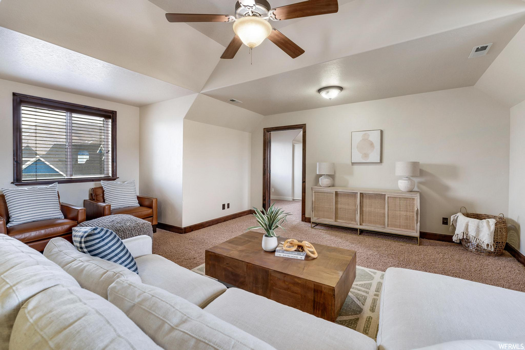 carpeted living room with a ceiling fan, natural light, and vaulted ceiling