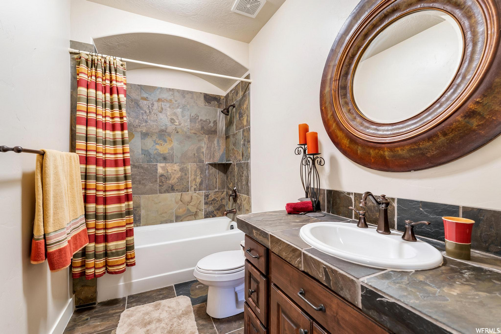 full bathroom with tile floors, toilet, mirror, shower curtain, oversized vanity, and washtub / shower combination