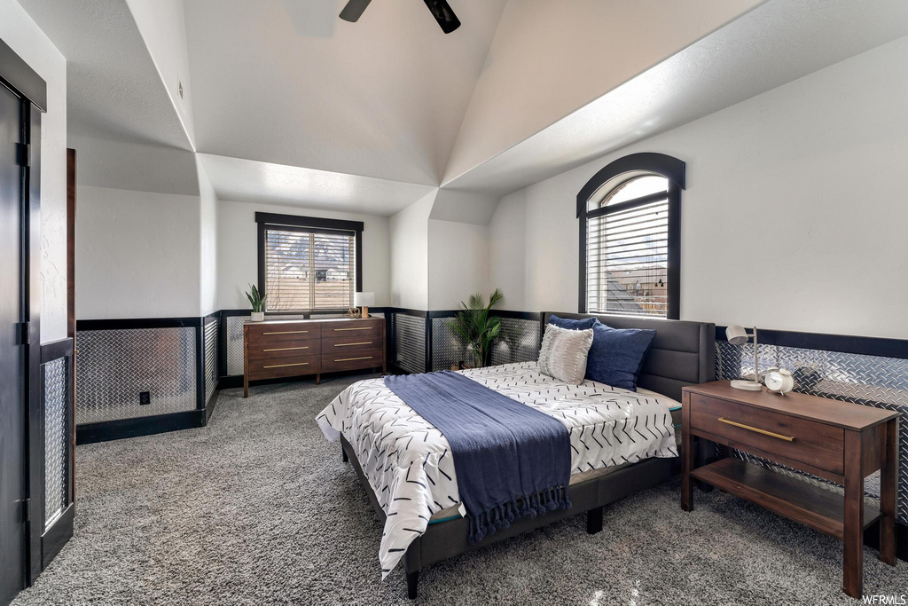 carpeted bedroom featuring multiple windows, vaulted ceiling, and a ceiling fan