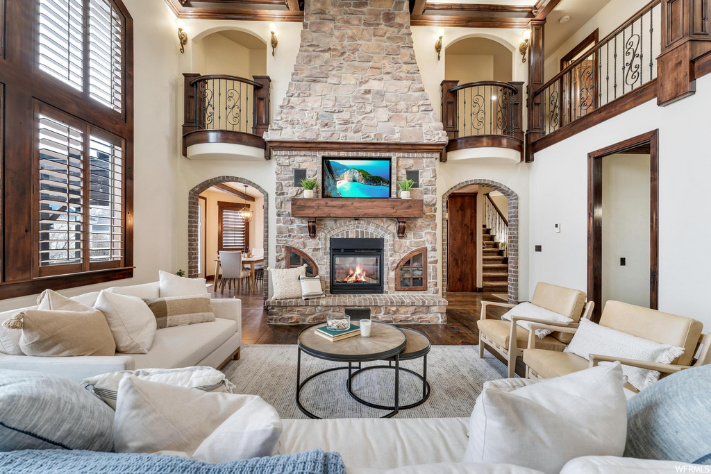 living room with a high ceiling, a fireplace, hardwood flooring, and a wealth of natural light