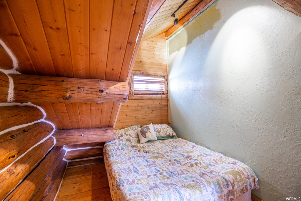 Bedroom with wood ceiling, wood-type flooring, vaulted ceiling, and wooden walls