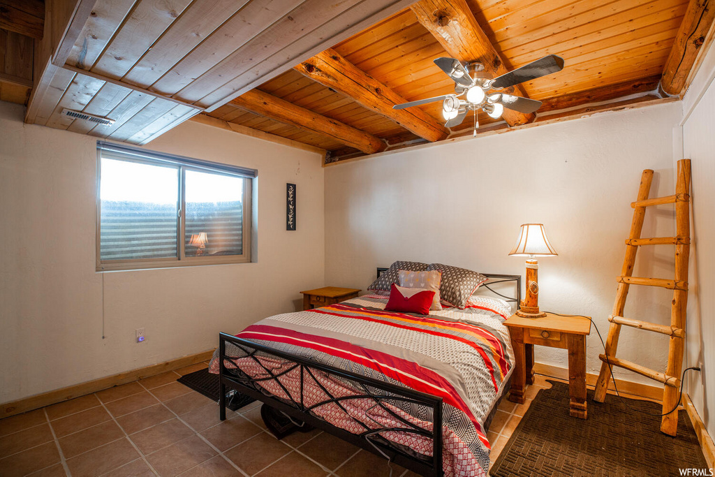 Bedroom with dark tile floors, ceiling fan, and wooden ceiling