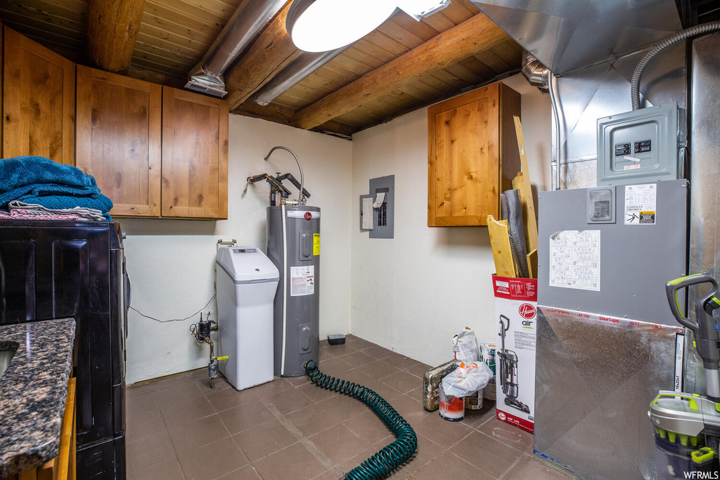 Washroom featuring wood ceiling, water heater, dark tile flooring, and cabinets