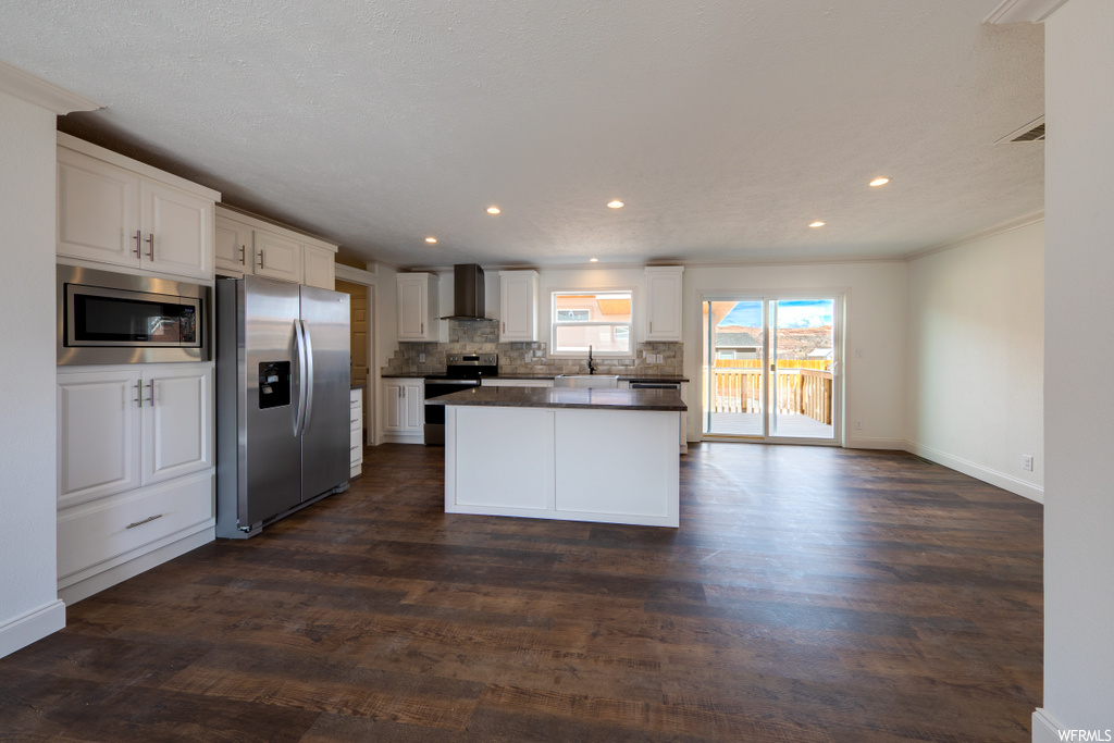 kitchen featuring natural light, refrigerator, ventilation hood, microwave, range oven, dark hardwood floors, and white cabinetry