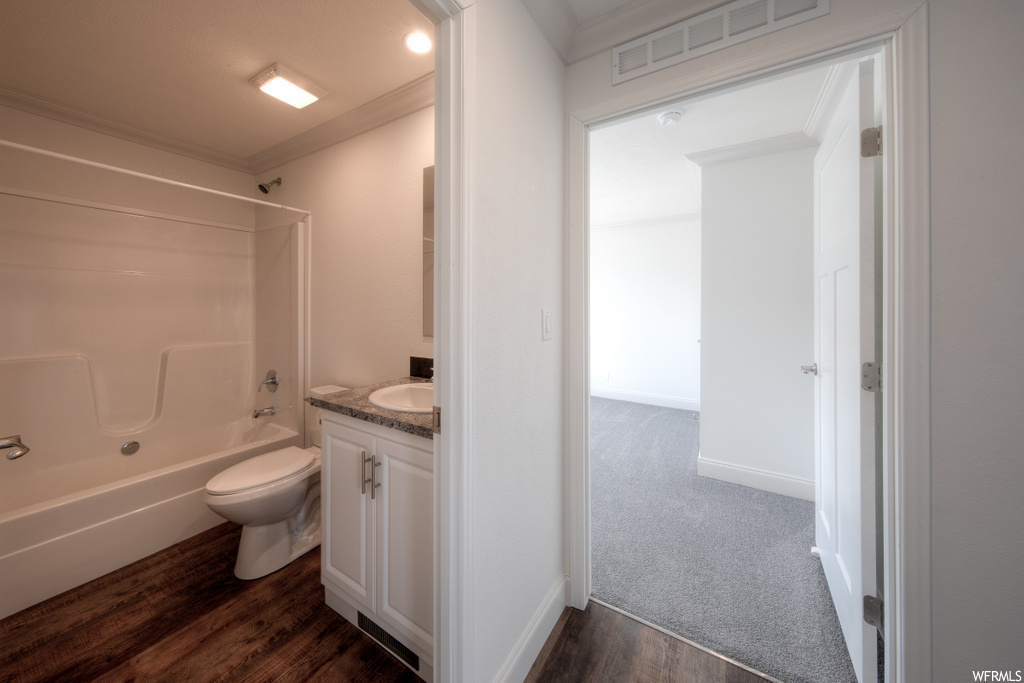 full bathroom with hardwood flooring, shower / washtub combination, toilet, and vanity