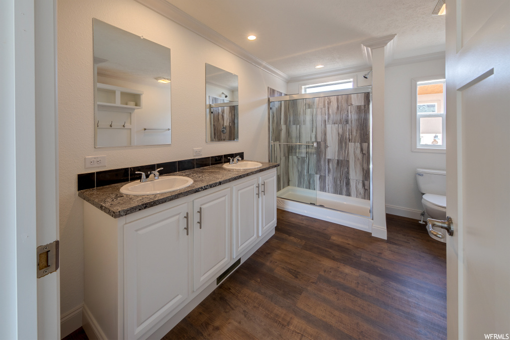 bathroom with natural light, hardwood floors, double large vanity, mirror, toilet, and a shower