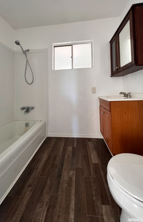 Full bathroom featuring hardwood flooring, vanity, mirror, shower / bath combination, and toilet