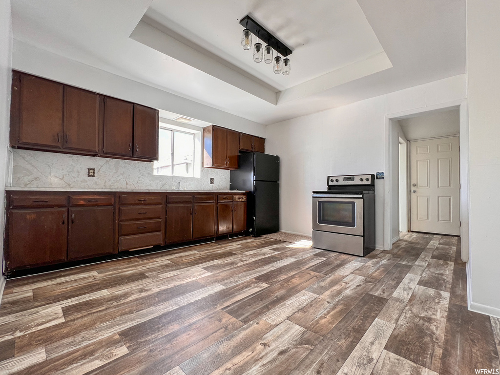 Kitchen featuring natural light, range oven, stainless steel refrigerator, dark hardwood flooring, and dark brown cabinetry