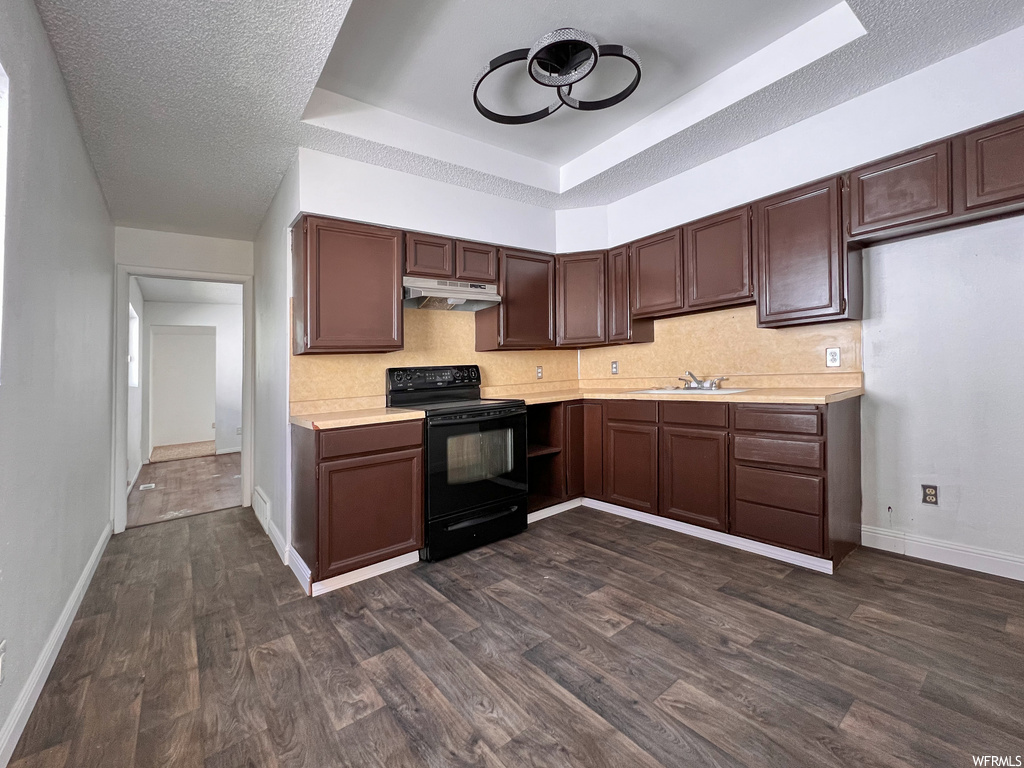 Kitchen featuring range oven, extractor fan, light countertops, dark brown cabinetry, and dark parquet floors