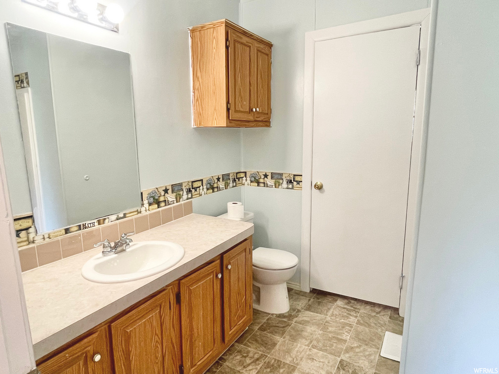 Half bathroom with tile floors, mirror, toilet, and vanity with extensive cabinet space