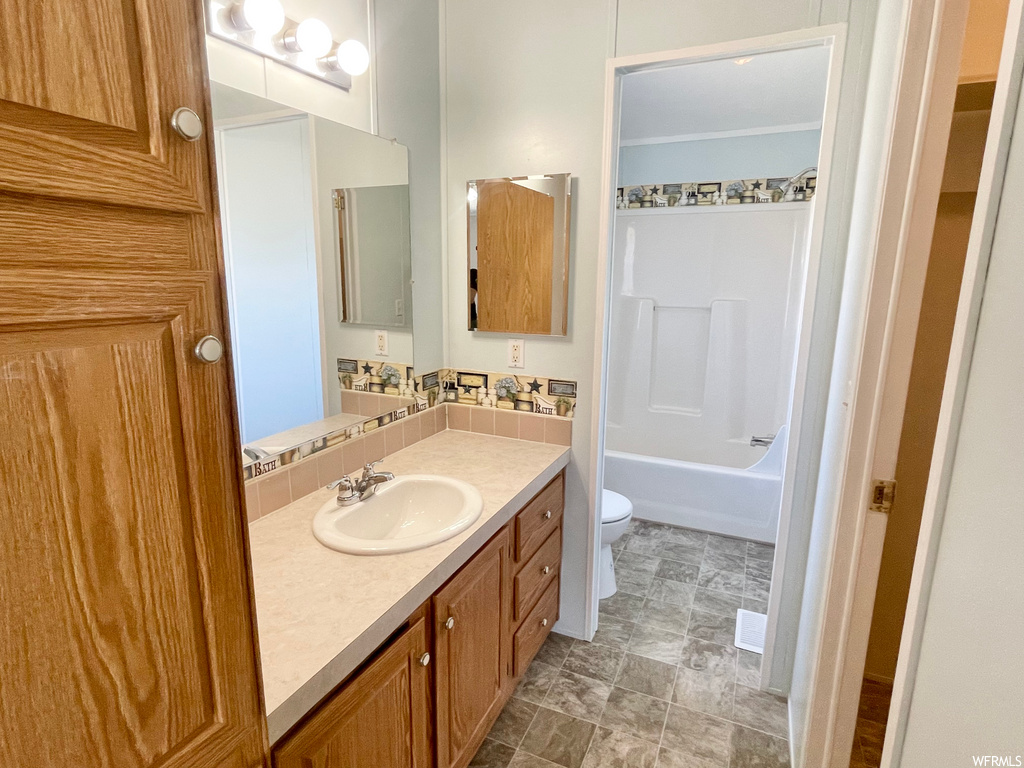 Full bathroom with tile flooring, mirror, toilet, tub / shower combination, and vanity