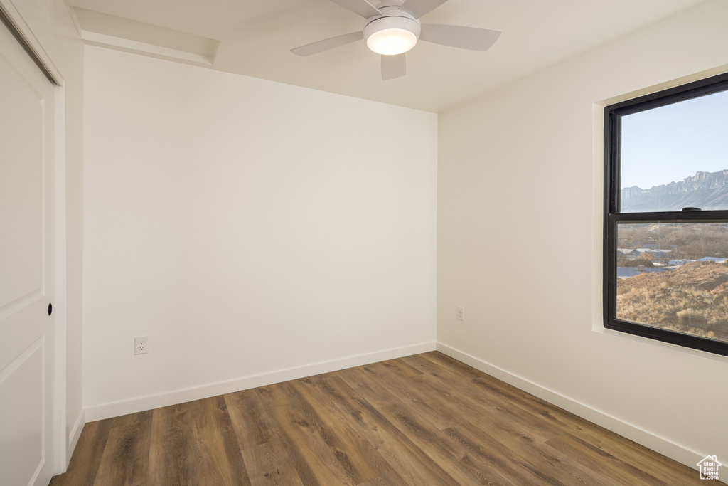Empty room featuring wood finished floors, baseboards, and a ceiling fan