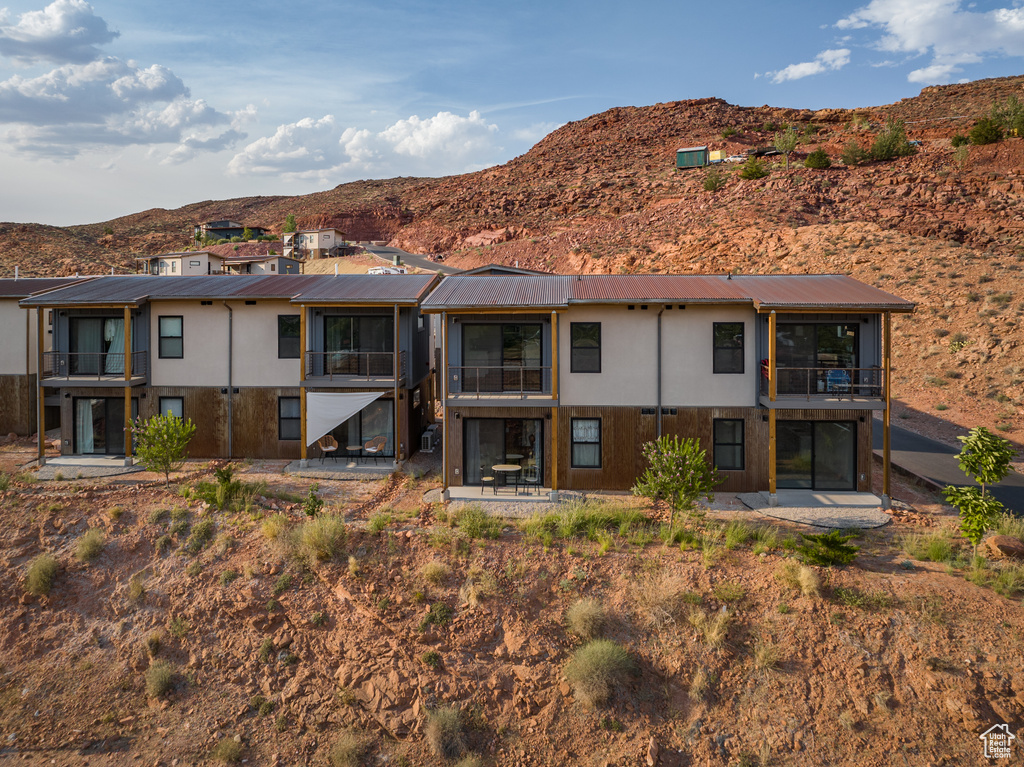 Back of house featuring a metal roof, a mountain view, and stucco siding