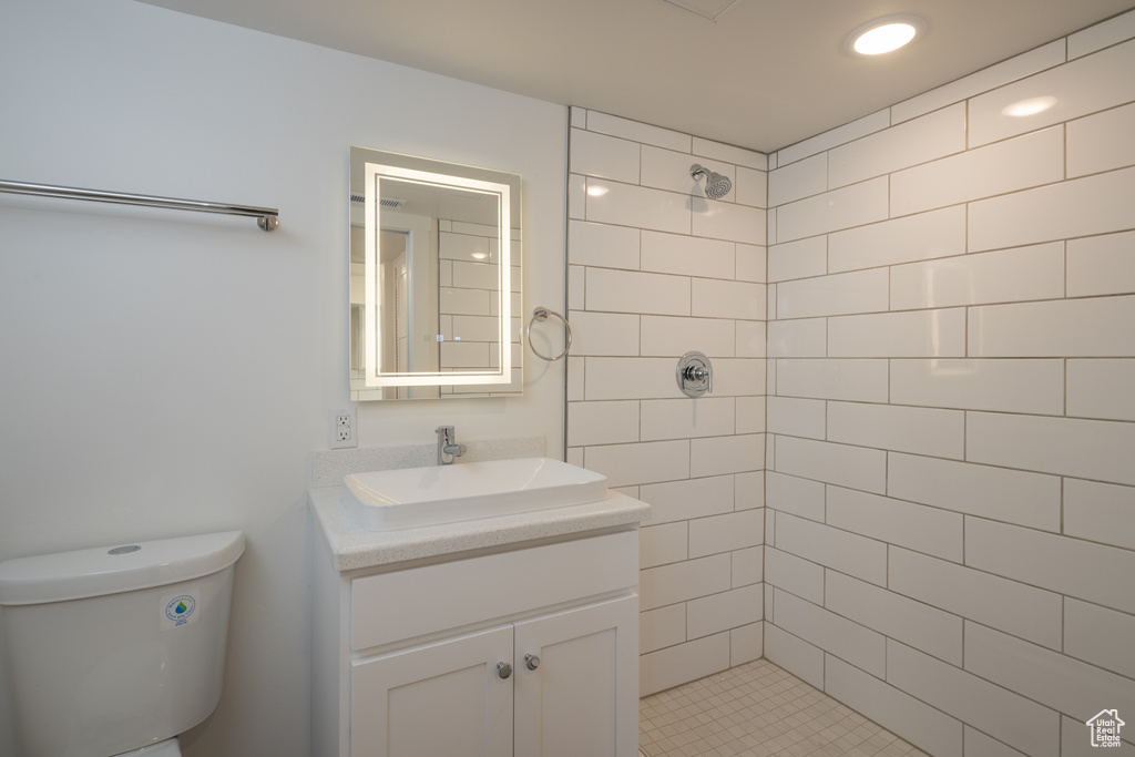 Full bath with tiled shower, vanity, and toilet