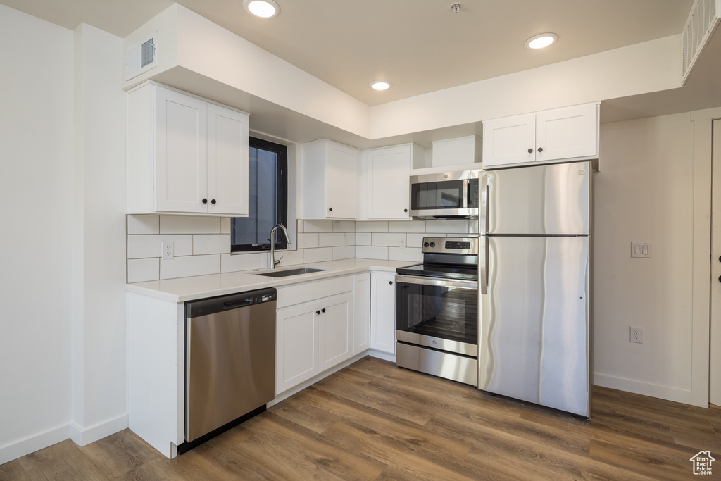 Kitchen with stainless steel appliances, a sink, white cabinetry, baseboards, and recessed lighting