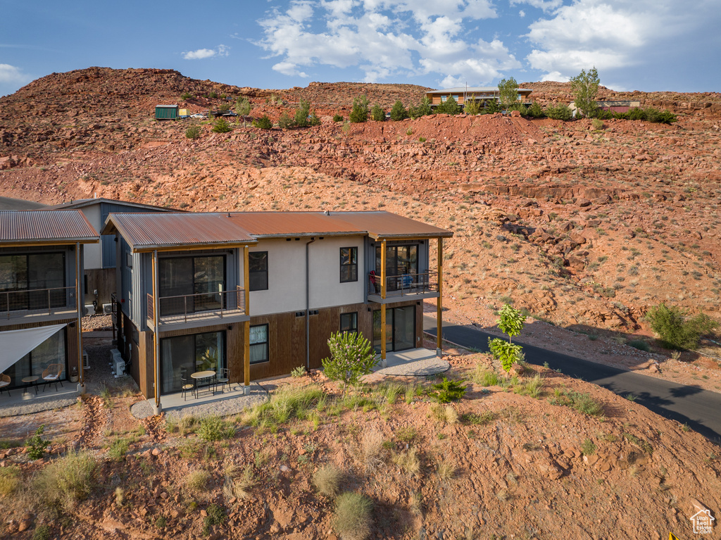 Back of property featuring a balcony, a patio area, a mountain view, and a metal roof
