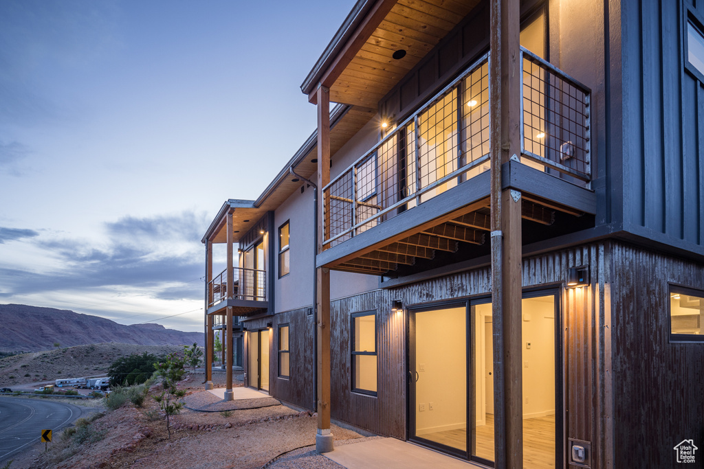Rear view of house with a balcony, a mountain view, and a patio