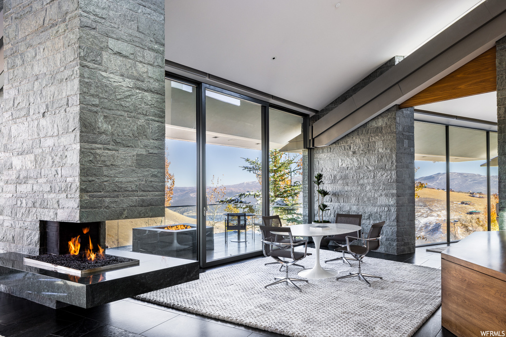 Interior space featuring light tile flooring, expansive windows, a healthy amount of sunlight, and a fireplace