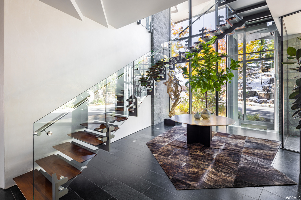 Stairs featuring a wealth of natural light, dark tile flooring, and a high ceiling