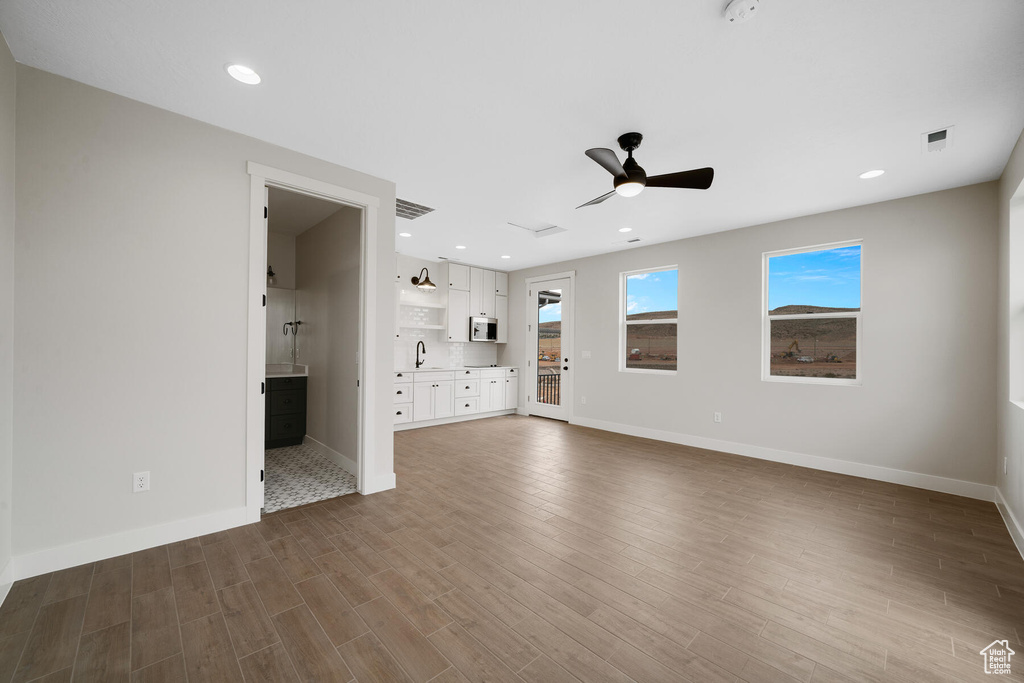 Unfurnished living room with ceiling fan, dark hardwood / wood-style flooring, and sink