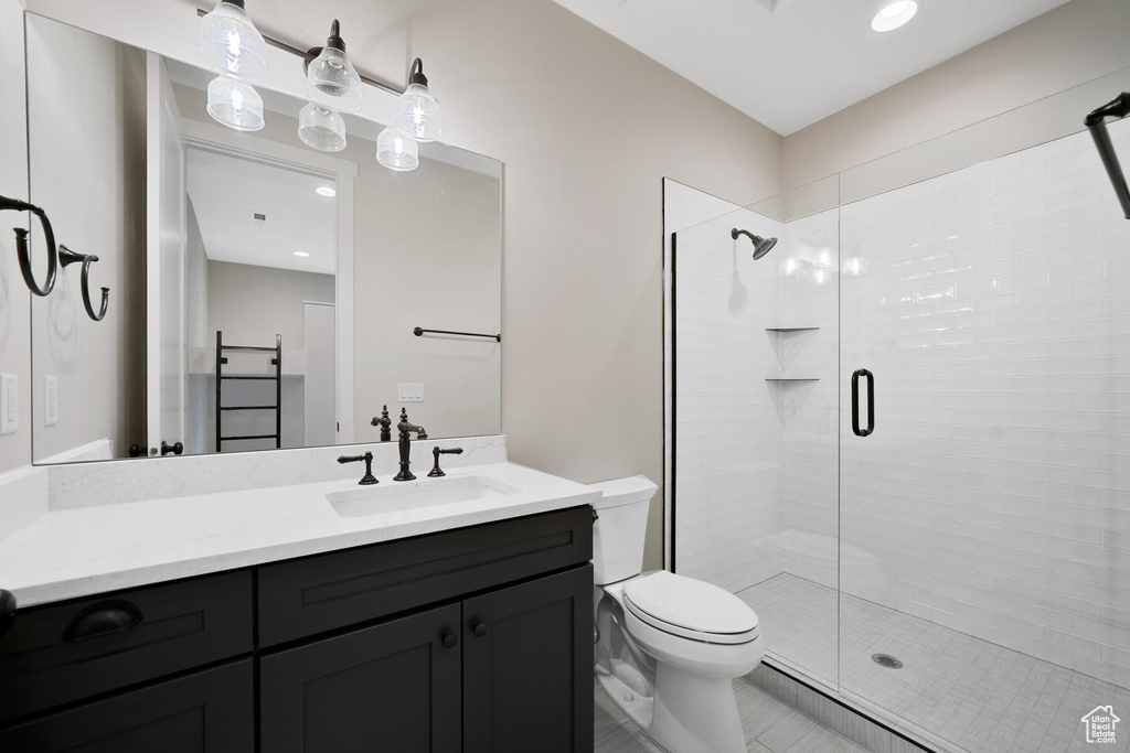 Bathroom featuring vanity, toilet, tile floors, and a shower with shower door