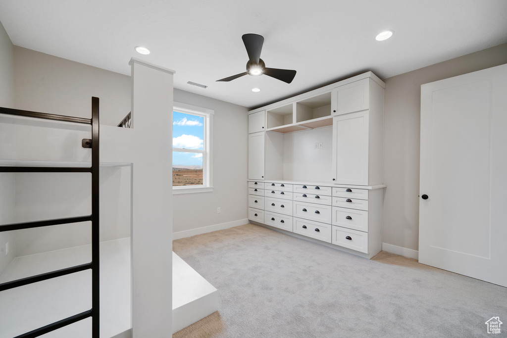 Spacious closet featuring light colored carpet and ceiling fan