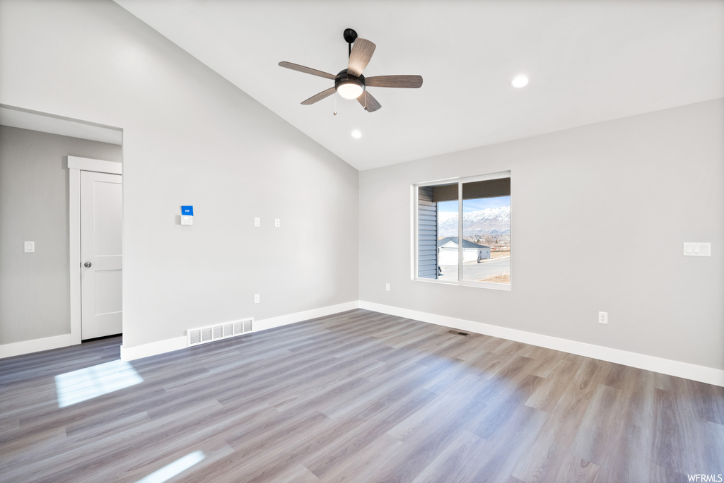empty room with natural light, vaulted ceiling, and hardwood flooring