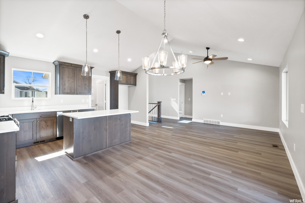 kitchen with a center island, lofted ceiling, light parquet floors, light countertops, and pendant lighting