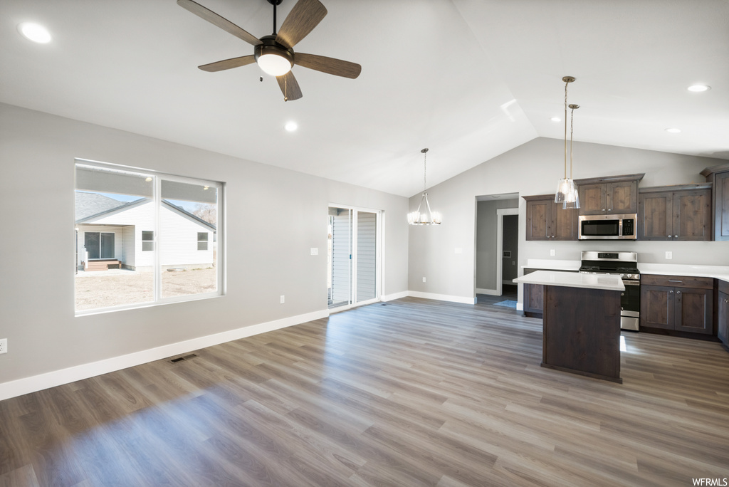kitchen featuring lofted ceiling, a ceiling fan, range oven, microwave, light countertops, dark brown cabinets, pendant lighting, and light parquet floors