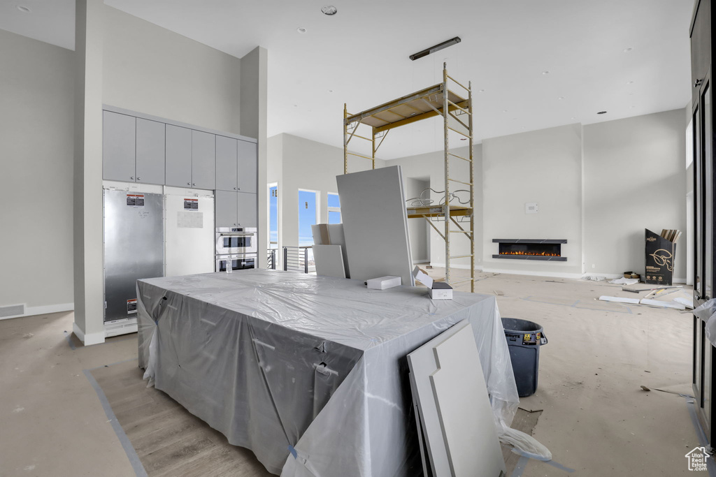 Kitchen featuring light stone counters, a towering ceiling, and stainless steel appliances