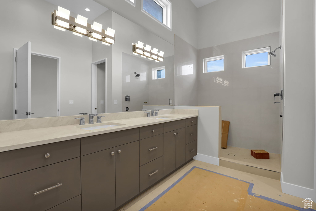 Bathroom with double vanity, a shower, and a towering ceiling