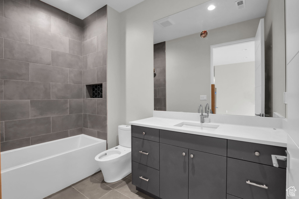 Full bathroom with tiled shower / bath, toilet, tile flooring, and oversized vanity