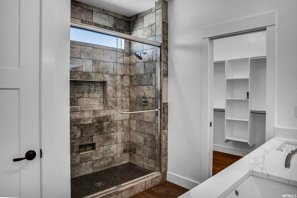 Bathroom with an enclosed shower, dual bowl vanity, and hardwood / wood-style floors