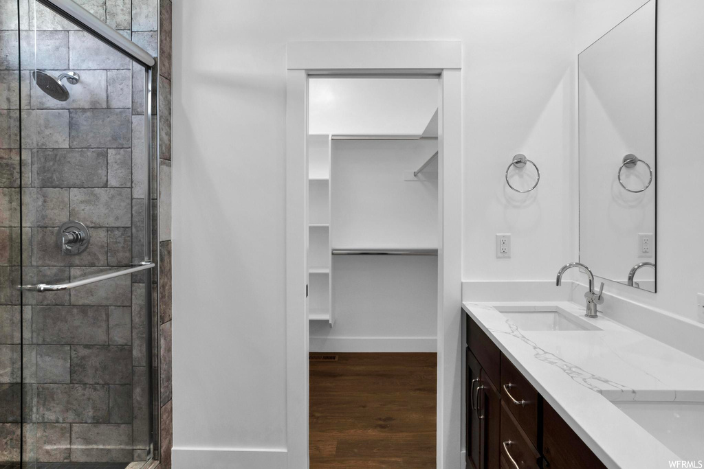 Bathroom featuring double sink, a shower with door, oversized vanity, and wood-type flooring