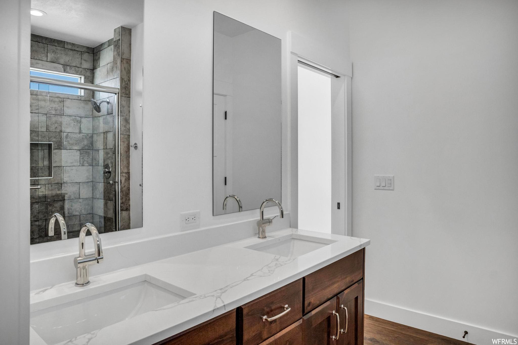 Bathroom with a shower with shower door, hardwood / wood-style floors, and dual bowl vanity