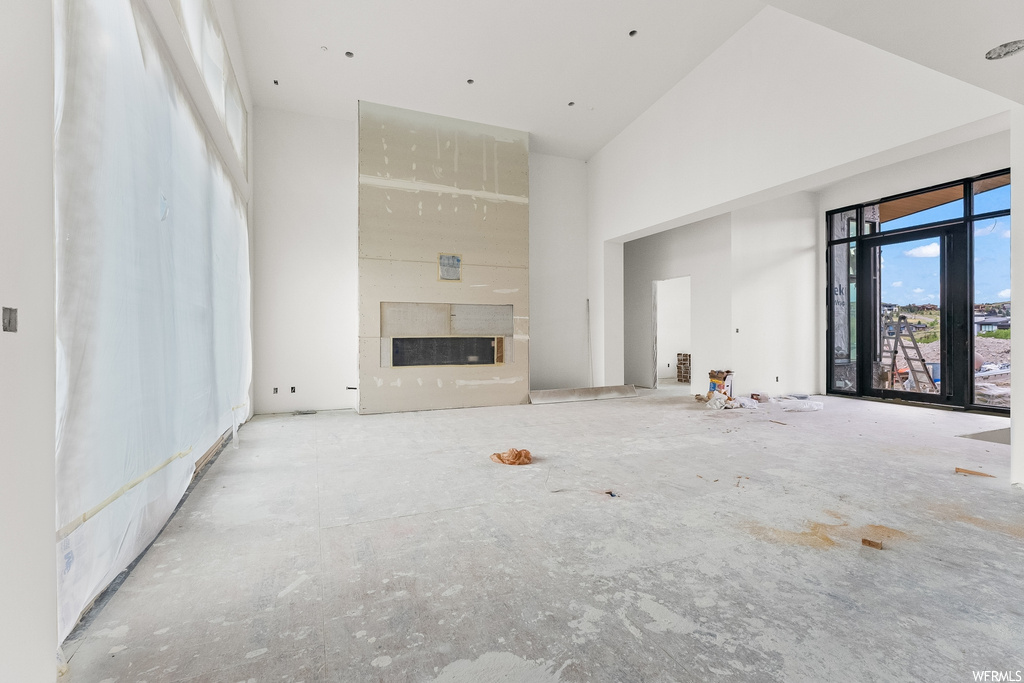 Unfurnished living room featuring a large fireplace and a towering ceiling