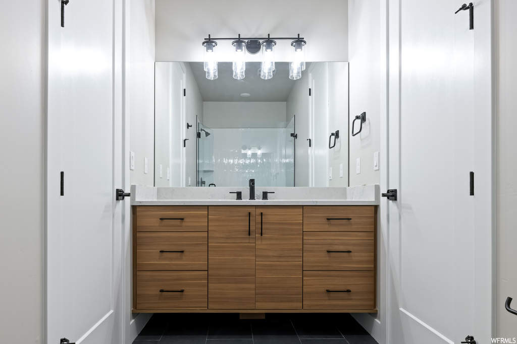 Bathroom featuring dark tile floors, mirror, and vanity