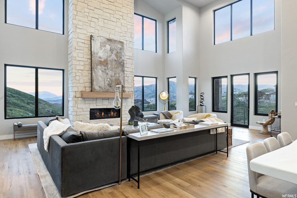 Living room featuring a high ceiling, light hardwood flooring, a healthy amount of sunlight, and a fireplace