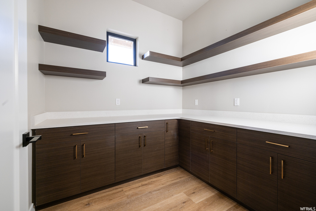 Kitchen with dark brown cabinetry, light countertops, and light hardwood floors