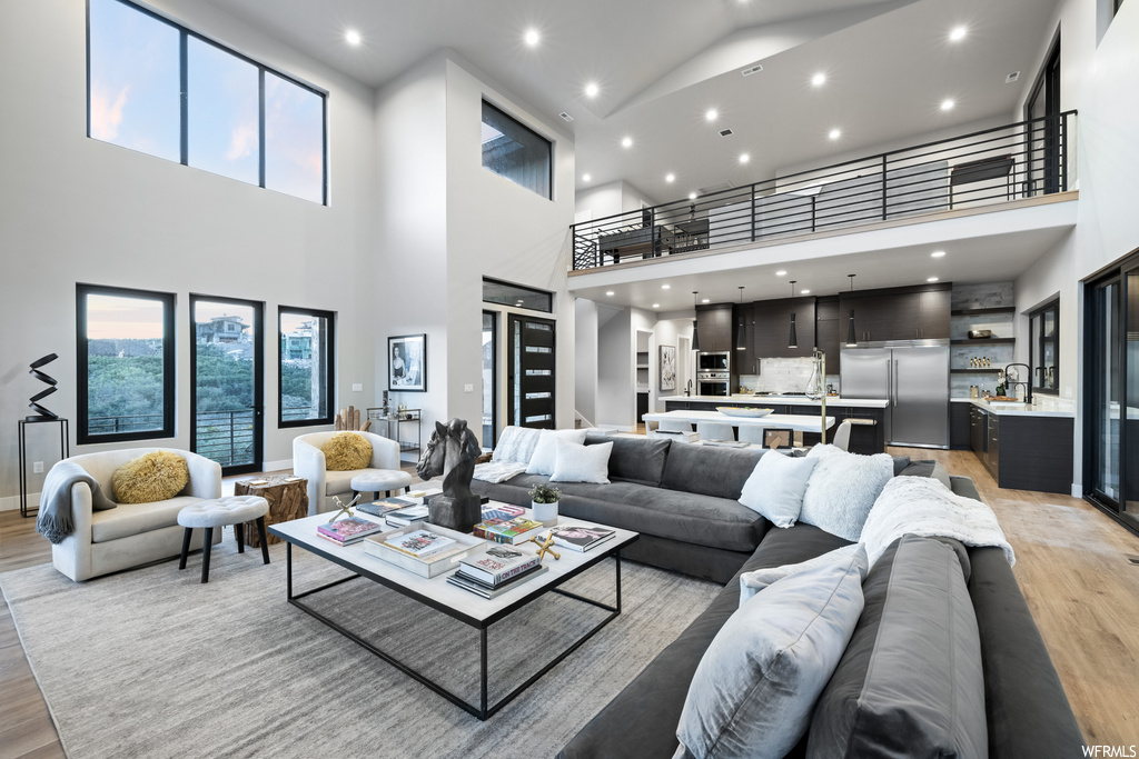 Hardwood floored living room with a high ceiling and a healthy amount of sunlight