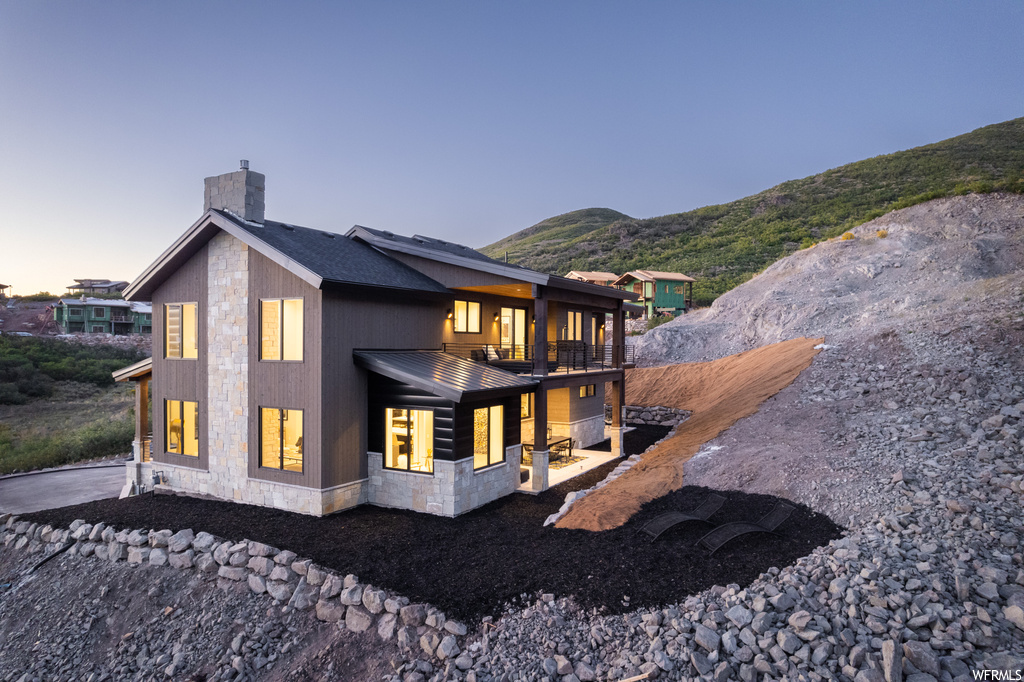 Back house at dusk featuring balcony and a mountain view