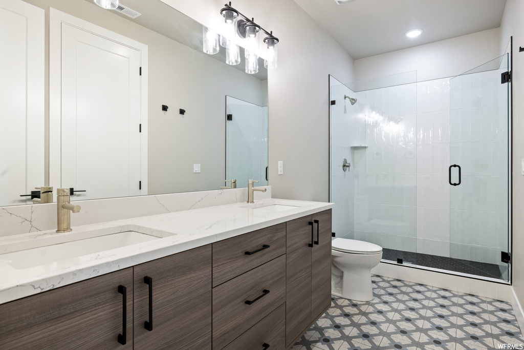 Bathroom featuring double large sink vanity, mirror, a shower with door, and light tile floors