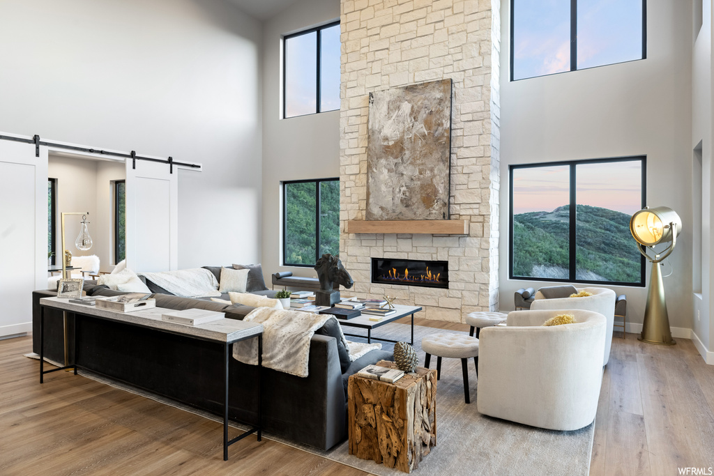 Living room with light hardwood flooring, a fireplace, and a high ceiling