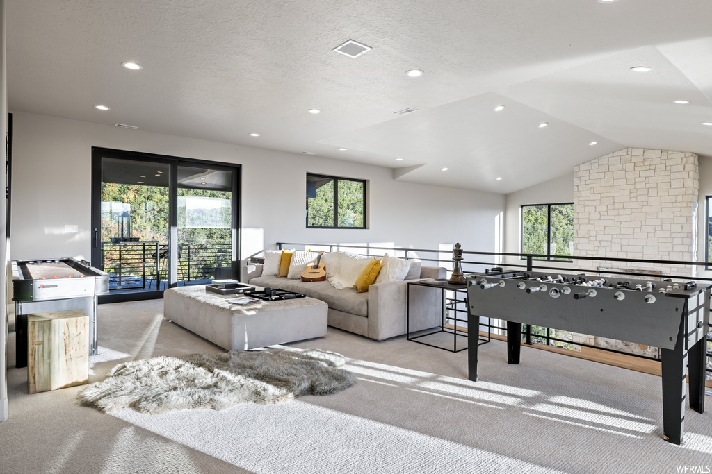 Living room with a wealth of natural light, light carpet, and lofted ceiling