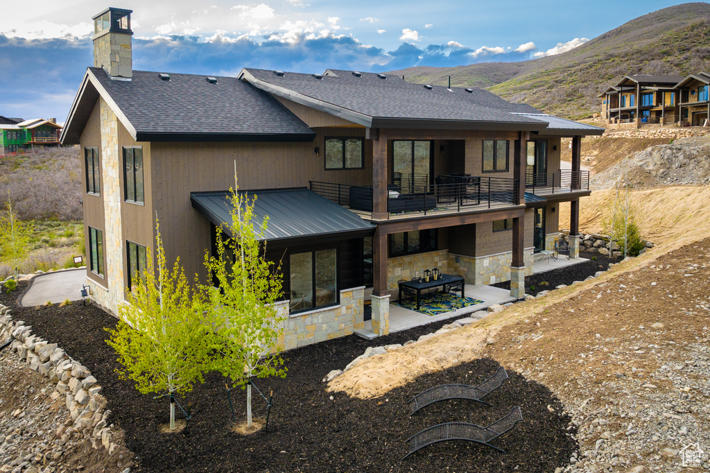 Rear view of property featuring a patio, an outdoor living space, a balcony, and a mountain view