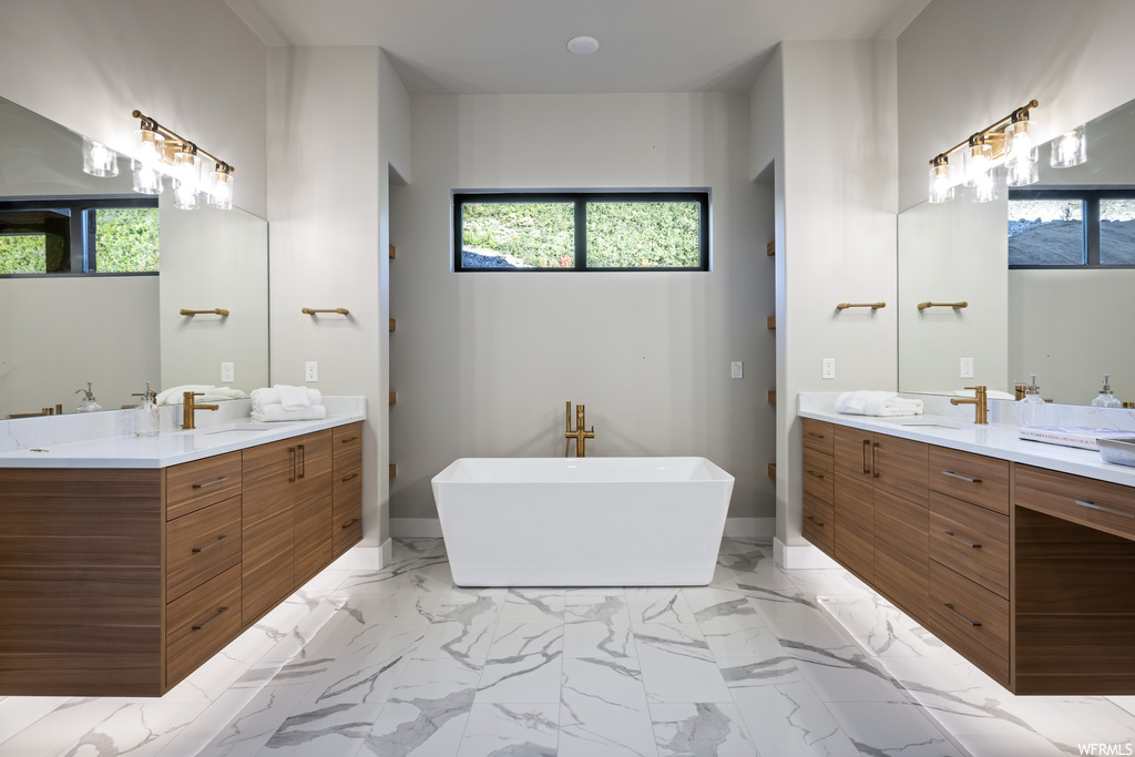 Bathroom with light tile flooring, a tub, mirror, and dual bowl vanity