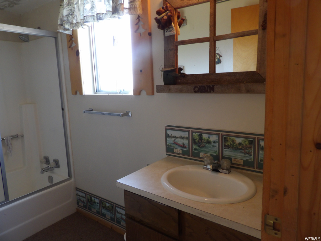 Bathroom with natural light, shower / bath combination with glass door, mirror, and large vanity