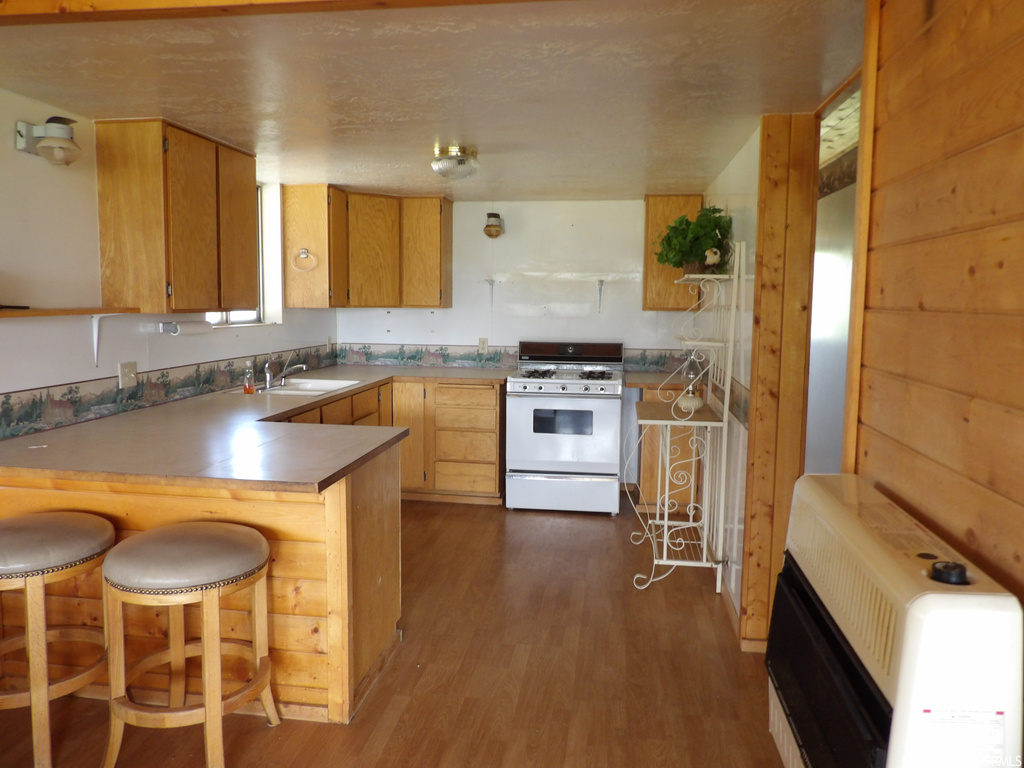 Kitchen with a kitchen breakfast bar, range oven, dark parquet floors, and brown cabinets