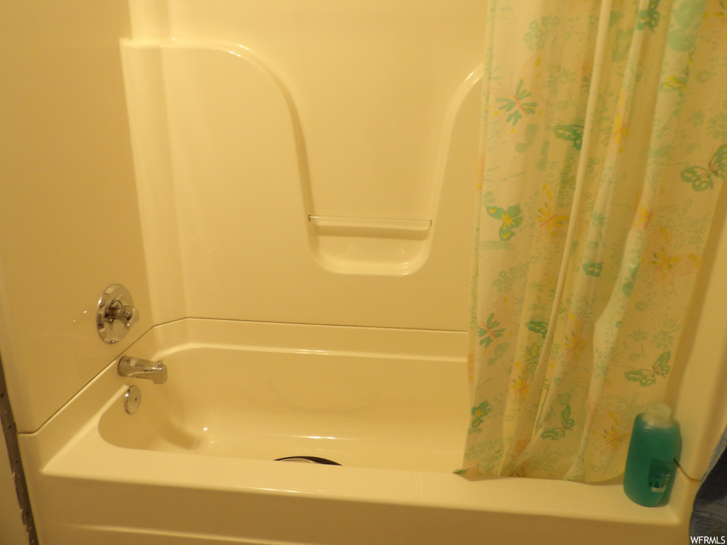 Bathroom featuring shower curtain and shower / washtub combination